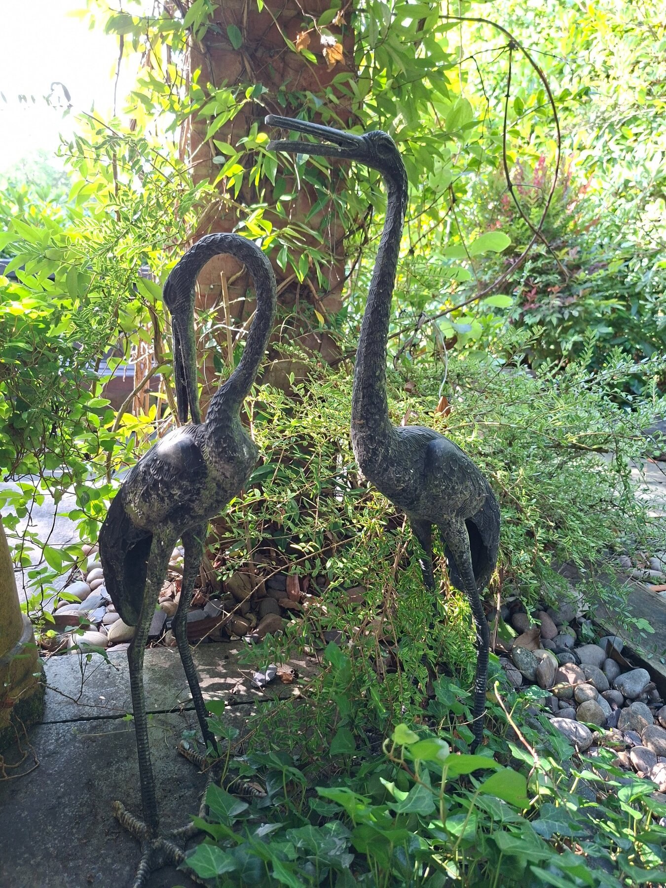 Pair of metal bird sculptures among lush planting