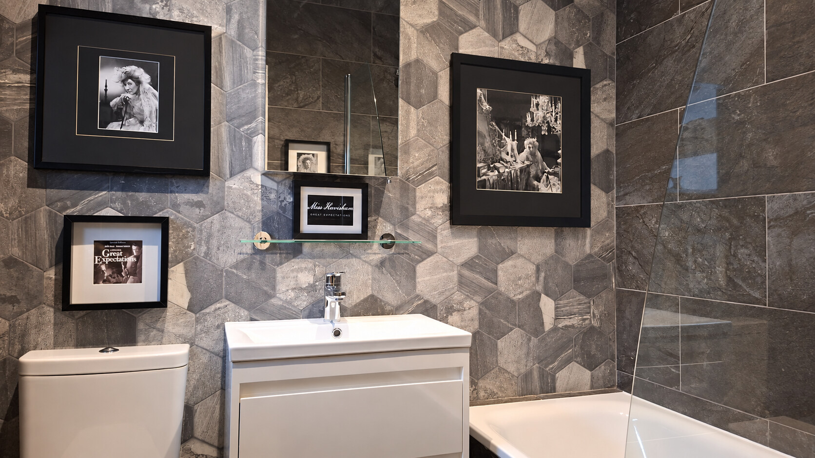 The Miss Havisham Bathroom with geometric grey tiles and a dramatic framed Miss Havisham scene above the bath